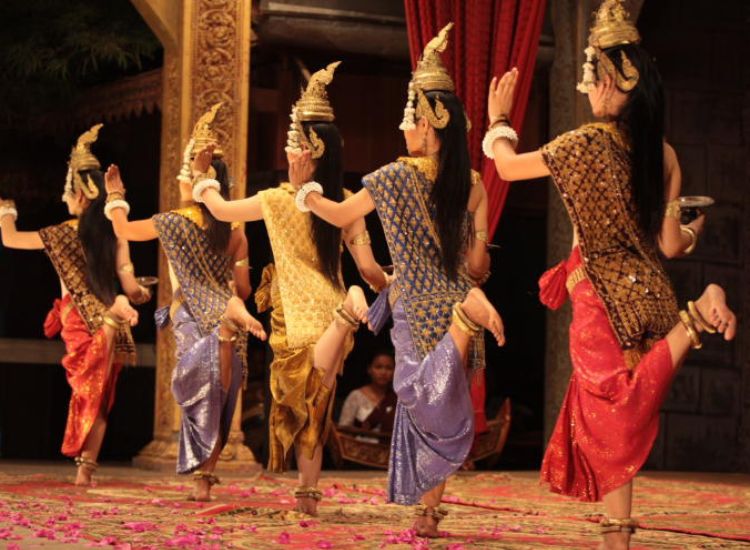 Cambodian dancers in traditional silk clothing performing a classical Khmer dance on stage in Siem Reap.
