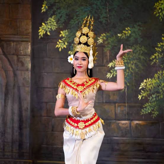 A Cambodian Apsara dancer posing with traditional hand gestures while wearing an intricate golden crown and dress.
