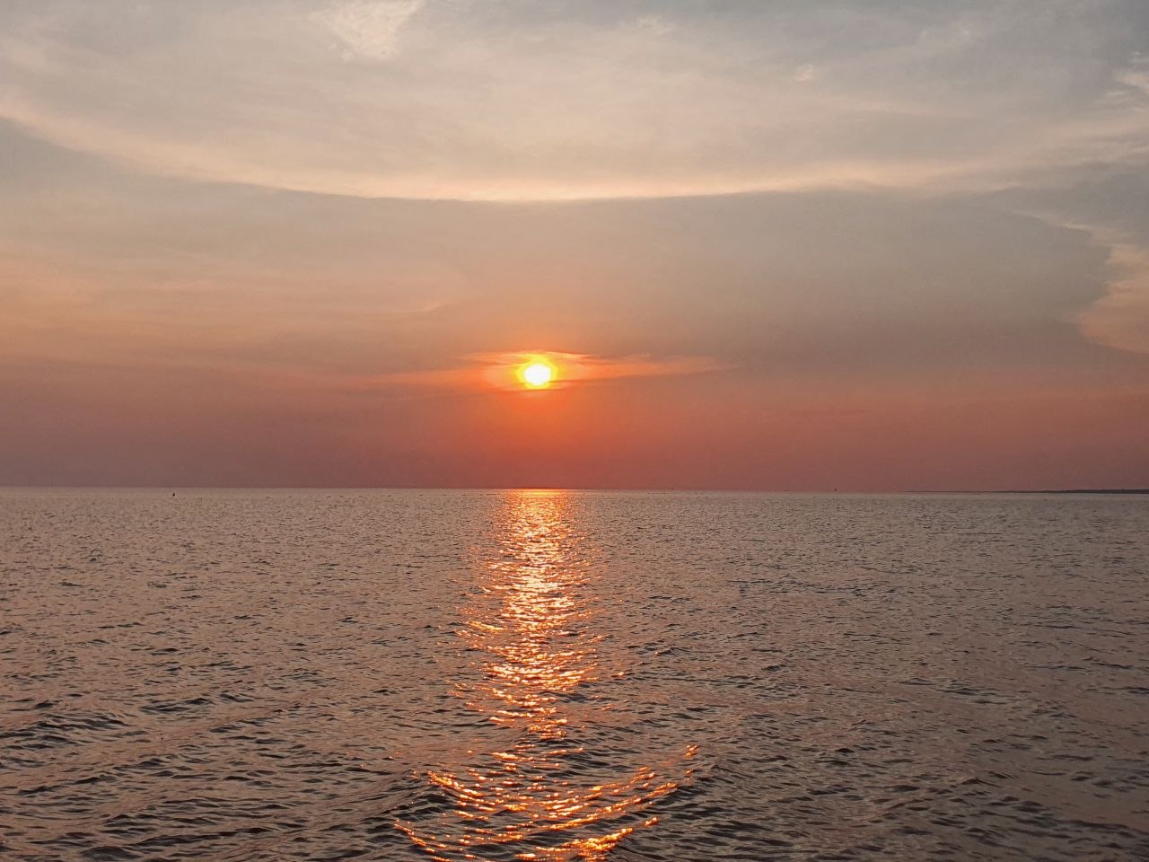 Soft golden sun setting over the vast calm waters of Tonle Sap Lake near Siem Reap Cambodia
