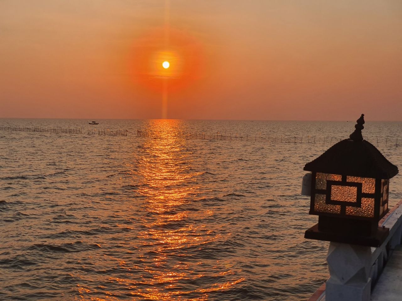 Golden sunset over Tonle Sap Lake with decorative stone lantern in the foreground near Siem Reap Cambodia