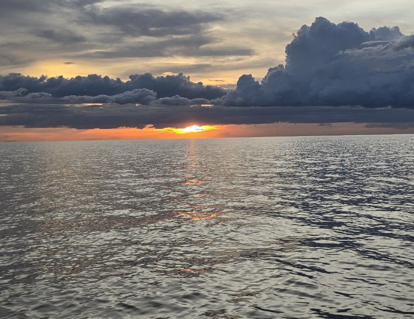 Sun setting behind dark clouds over the expansive waters of Tonle Sap Lake near Siem Reap