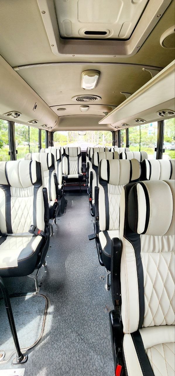 Interior view of a luxury tourist bus featuring plush black and white leather reclining seats and central aisle
