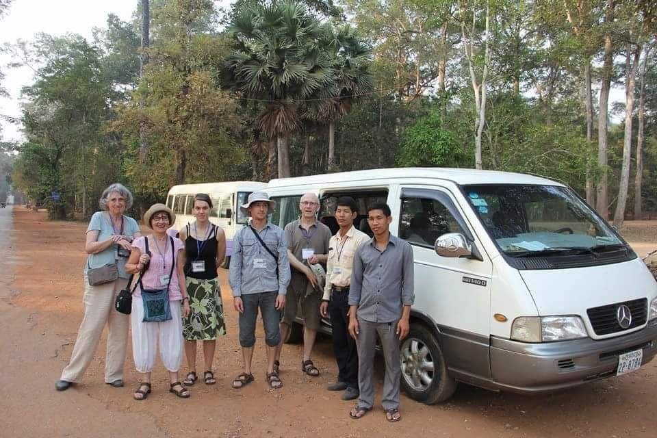 Group of international tourists standing next to a white Mercedes passenger van with local drivers