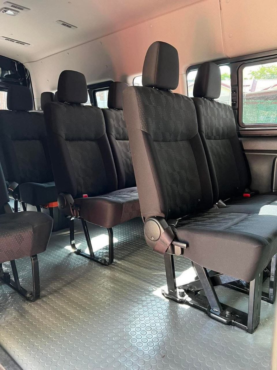 Clean interior of a modern passenger van with comfortable black fabric seating rows and air conditioning
