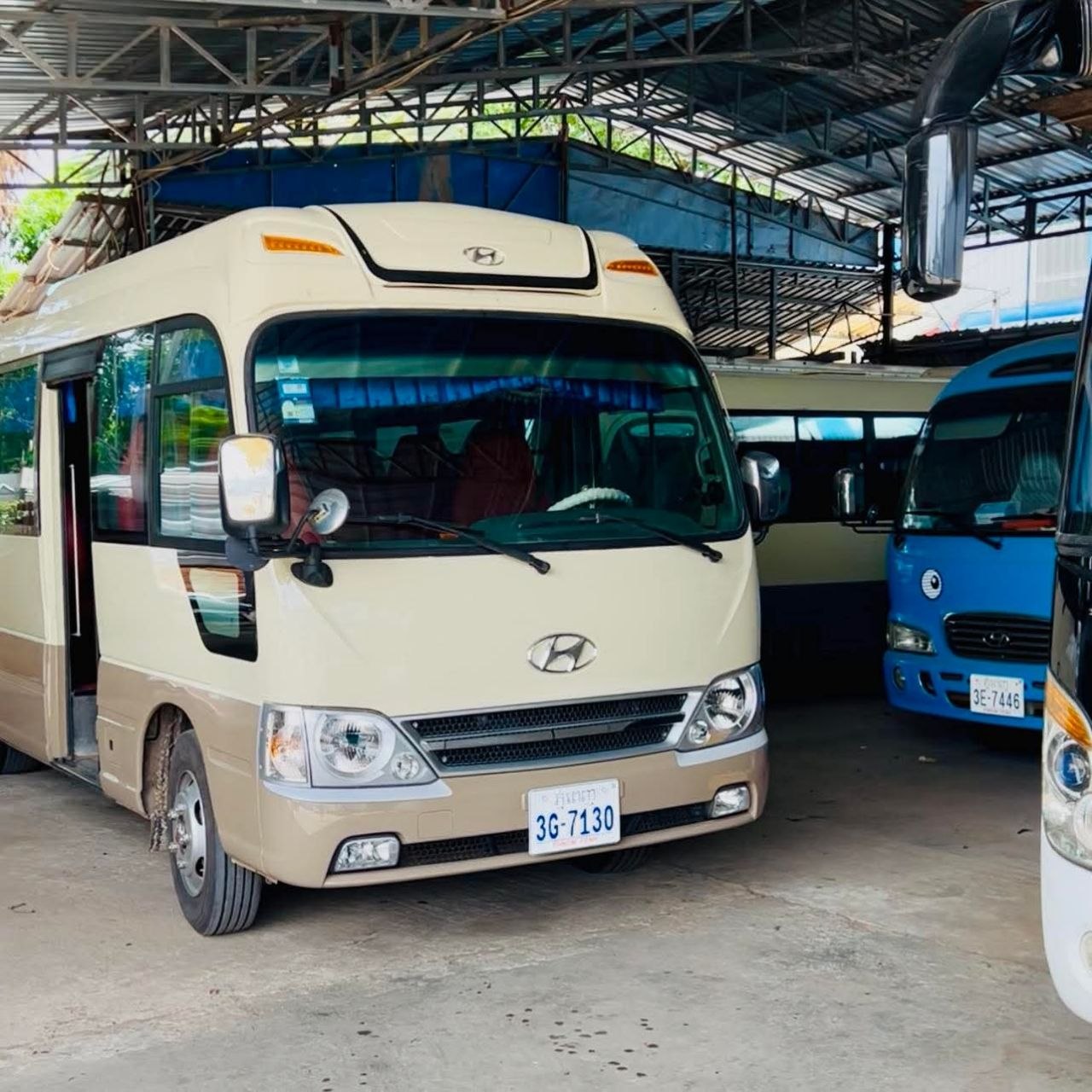 Cream and tan Hyundai County tourist minibus parked inside a covered garage in Siem Reap